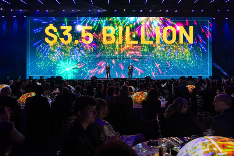 Stage at the Go For Launch liftoff event with "3.5 Billion" on the screen behind speakers with firework imagery
